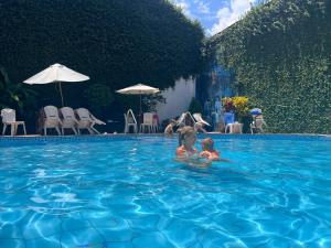 伊基托斯El Cauchero Hotel Iquitos的两个孩子在游泳池游泳