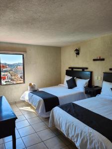 瓜纳华托Hotel 1988 Guanajuato的酒店客房设有两张床和窗户。