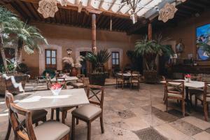 帕茨库卡罗El Edén Hotel Boutique的一间设有桌椅的餐厅,种植了棕榈树