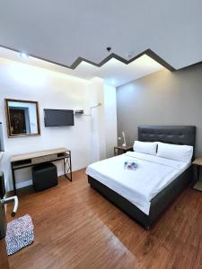奥隆阿波New Kong's Hotel的一间卧室配有一张床、一张书桌和一台电视