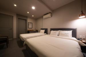 釜山No25 Hotel Yeonsan的酒店客房,配有两张带白色床单的床