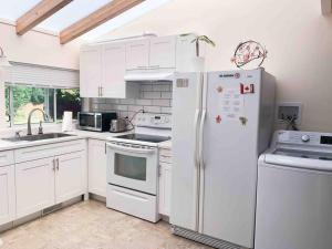 萨里Separate access suite , separate kitchen, bathroom的厨房配有白色橱柜和白色冰箱。