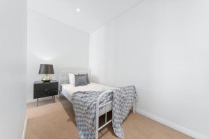 悉尼Skyview Comfy Apt in Centre of Burwood的白色卧室配有床和椅子