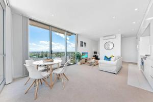 悉尼Skyview Comfy Apt in Centre of Burwood的厨房以及带桌椅的起居室。