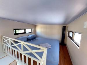 别霍港Tiny house with extended camping area for large groups的一间卧室设有蓝色的床和2个窗户。