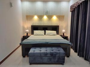 拉合尔Fully Serviced Holiday Home Near Lahore Ring Road的一间卧室配有一张大床和蓝色的搁脚凳