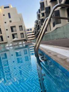 迪拜Brand New Studio Near Dubai Airport的一座游泳池,旁边是一座建筑物,上面有金属栏杆
