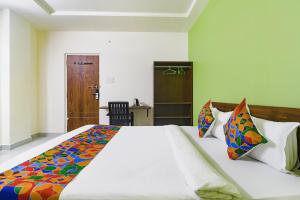 海得拉巴FabHotel Golden Hitech的卧室配有一张带彩色枕头的大型白色床。