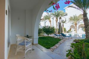 迈来亚Palm Djerba Suites的一个带椅子和棕榈树的庭院和一个游泳池