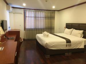 巴色Nakhone Champa Hotel的配有一张床和一张书桌的酒店客房