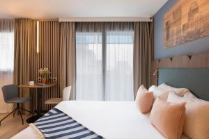库尔布瓦馨乐庭巴黎德芬斯酒店的酒店客房设有一张大床和一张书桌。