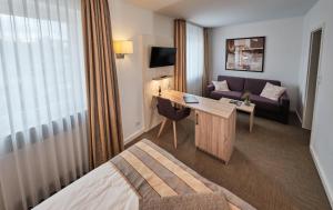 波恩阿德勒高级酒店的酒店客房配有一张床、一张书桌和一张沙发。
