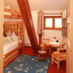HeimenkirchAndreashof的一间卧室配有一张双层床、一张桌子和一张书桌。