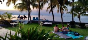 罗威那1000梦幻简易别墅酒店的一群人坐在海滩附近的草地上
