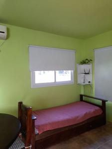 马德拉潘帕斯Quetrihue的绿色卧室设有一张带窗户的床
