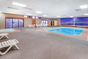 佩里斯堡Baymont by Wyndham Perrysburg-Toledo的一个带桌椅的房间,一个大型游泳池