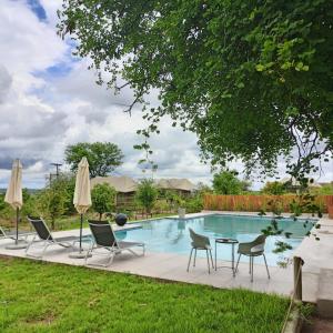 ChobeXhabe Safari Lodge Chobe的一个带桌椅和遮阳伞的游泳池