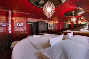 久洛科文酒店的餐厅设有白色桌子、红色墙壁和吊灯