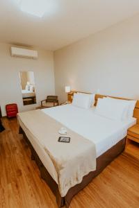 维多利亚Vitoria Praia Hotel的铺有木地板的客房内一张大白色的床