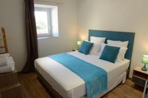 SavasGîte de Laphine avec Spa Privé的一间卧室配有一张带蓝白色枕头的大床
