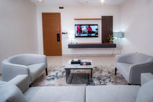 阿布贾Wali's Suites的客厅配有两把椅子和电视