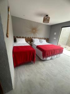 圣米格尔-杜斯米拉格里斯Nauru chalés milagres的卧室内的两张床,配有红色和白色床单