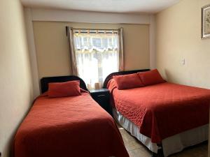 克萨尔特南戈Apartamento #2 Portal de Occidente的一间卧室设有两张带红色床单的床和窗户。