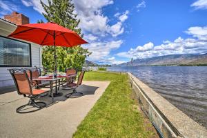 OrovilleWaterfront Osoyoos Lake Cottage with Beach and Patio!的水边带雨伞的桌椅