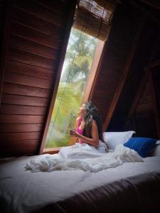 乌纳瓦图纳Sky View Cabin Unawatuna的坐在床上看着窗外的女人