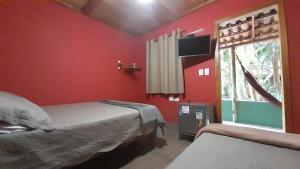 库穆鲁沙蒂巴Chalés Guigó-Cumuruxatiba的红色卧室设有两张床和窗户