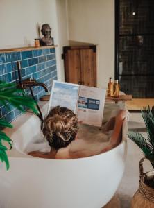 RossumLandgoed Lodges Scholten Linde的浴缸里的人读杂志