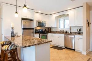 萨尼贝尔SANDPIPER BEACH 205的厨房配有白色橱柜和花岗岩台面