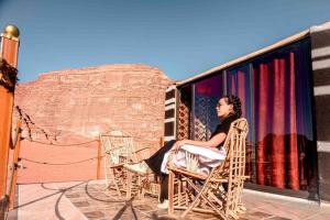 瓦迪拉姆瓦迪鲁姆天空之旅营地旅馆的坐在阳台上椅子上的女人