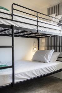 穆卢拉巴Abode Mooloolaba, Backpackers & Motel rooms的卧室配有2张双层床和白色床单