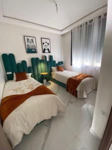 拉巴特Neuf et raffiné, centre ville Rabat的一间卧室配有两张带绿椅的床