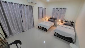 Ban Bang KrasanBed&Breakfast@Bangpa-in Hostel的配有窗帘和灯的客房内的两张床