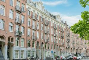 阿姆斯特丹Central Rooftop Terrace Guest Suite的一座大型砖砌建筑,前面有汽车停放