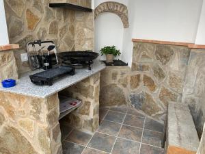 马尔帕尔蒂达德卡塞雷斯Casa rural Maila的一个带烧烤架和石墙的厨房