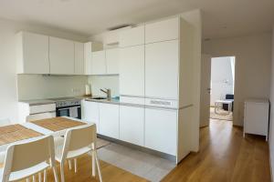 维也纳Central Living Apartments - Belvedere的厨房配有白色橱柜和桌椅