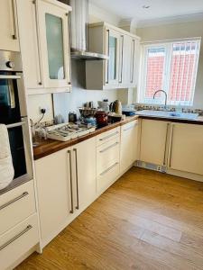 赫尔Cosy 3-bed house的厨房铺有木地板,配有白色橱柜。