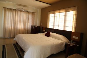 Perintalmannahazmi inn的卧室配有白色的床和红色枕头