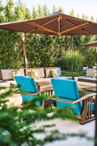 帕埃斯图姆Savoy Hotel & Spa - Preferred Hotels & Resorts的两把蓝色的椅子和一张桌子放在伞下