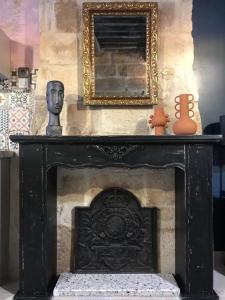 于泽斯Le 6 Bis by Les Cailloux Dorés的黑色壁炉,配有雕像和镜子