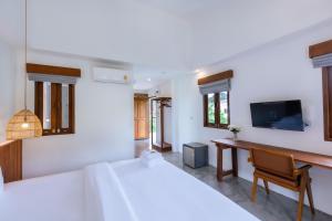 攀牙Phang Nga Origin Hotel的一间卧室配有两张床、一张桌子和一台电视。