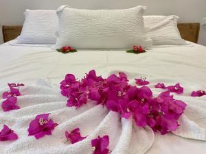 吉汶瓦Tangawizi Villa with Private Pool ZanzibarHouses的白色的床,上面有紫色的花