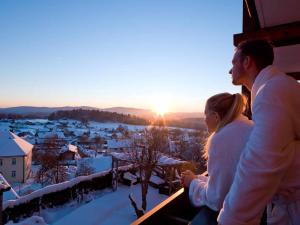 施皮格劳葛洛鲍尔全景酒店的男人和女人站在阳台上欣赏日落