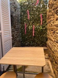 福什科阿新镇Apartamentos Barbosa的墙上的木桌,上面有粉红色的花朵