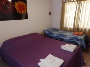 卢汉德库约Departamento Carrodilla Luján的一间客房配有两张床和一张紫色桌子上的毛巾
