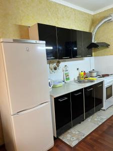 阿拉木图Marzhan Apartments的厨房配有白色冰箱和黑色橱柜。