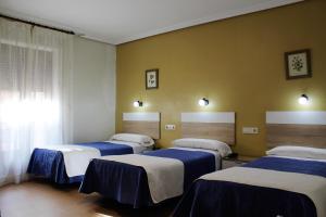 托莱多马德里旅馆的一间设有4张床、蓝色和白色床单的客房